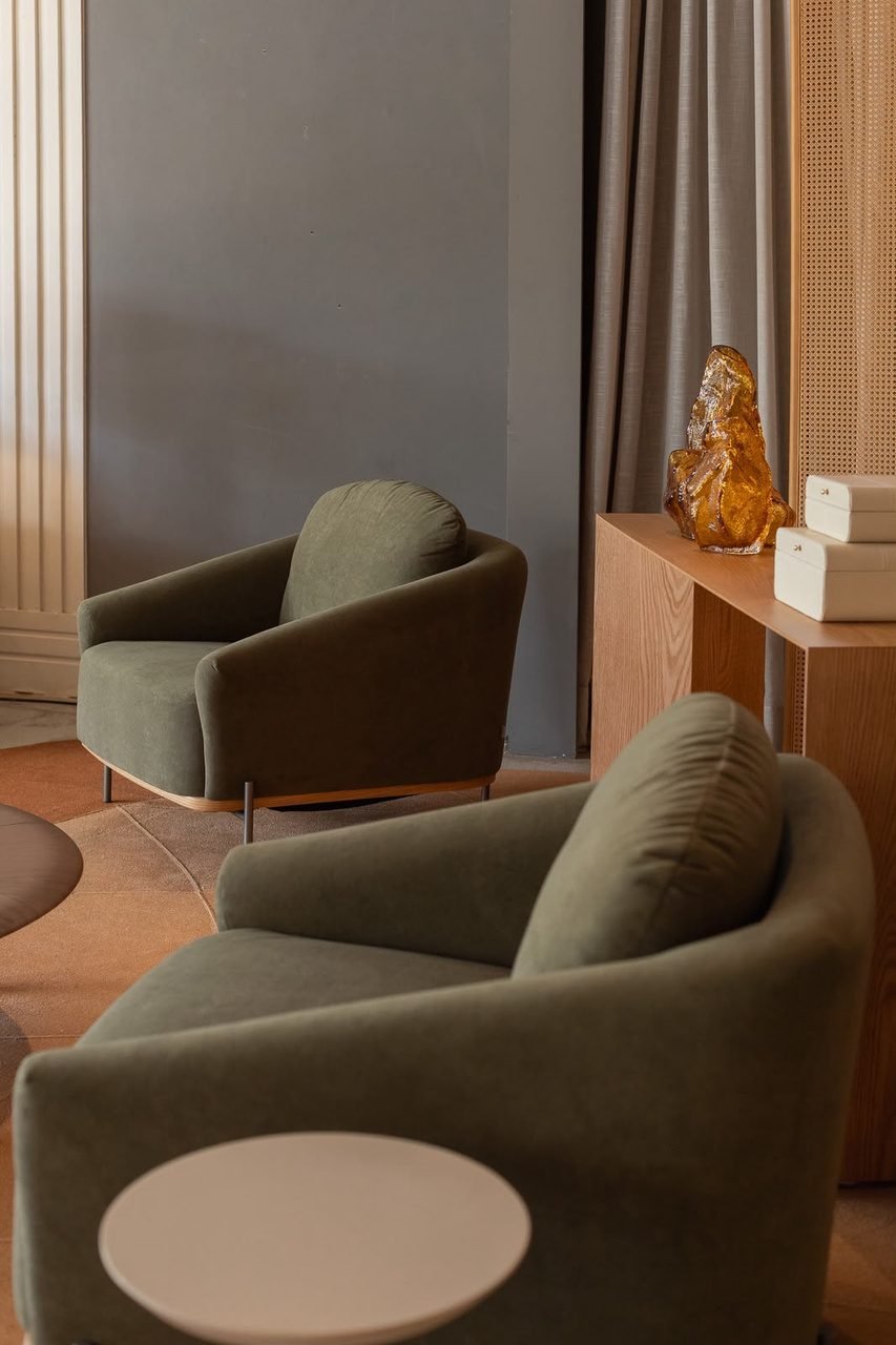 Poltronas verdes em lounge corporativo com aparador de madeira